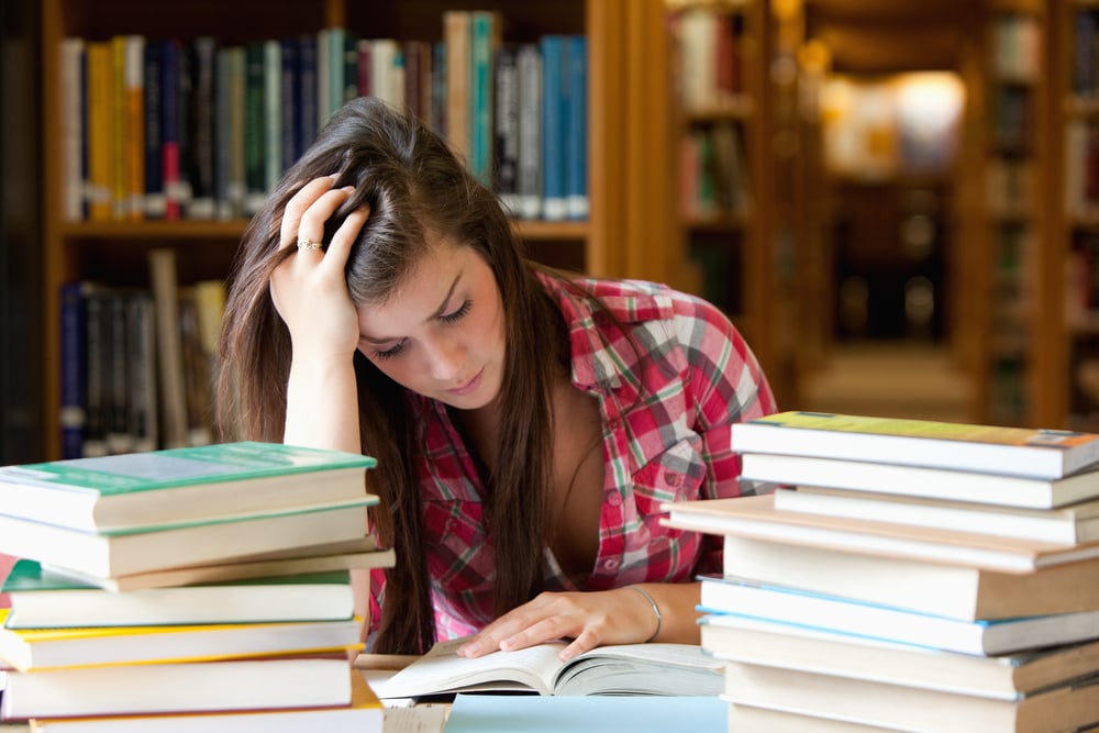 Focused student surrounded by books in a library Focused student surrounded by books in a library